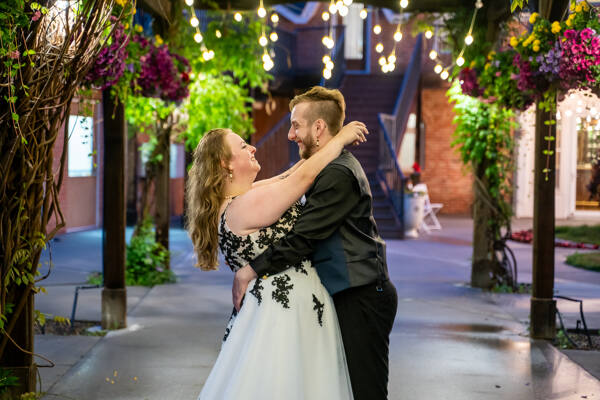 Bride and groom dancing joyfully under string lights at an outdoor wedding venue